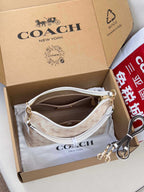Light beige patterned crossbody bag with white strap, gold hardware, and inner zip opening