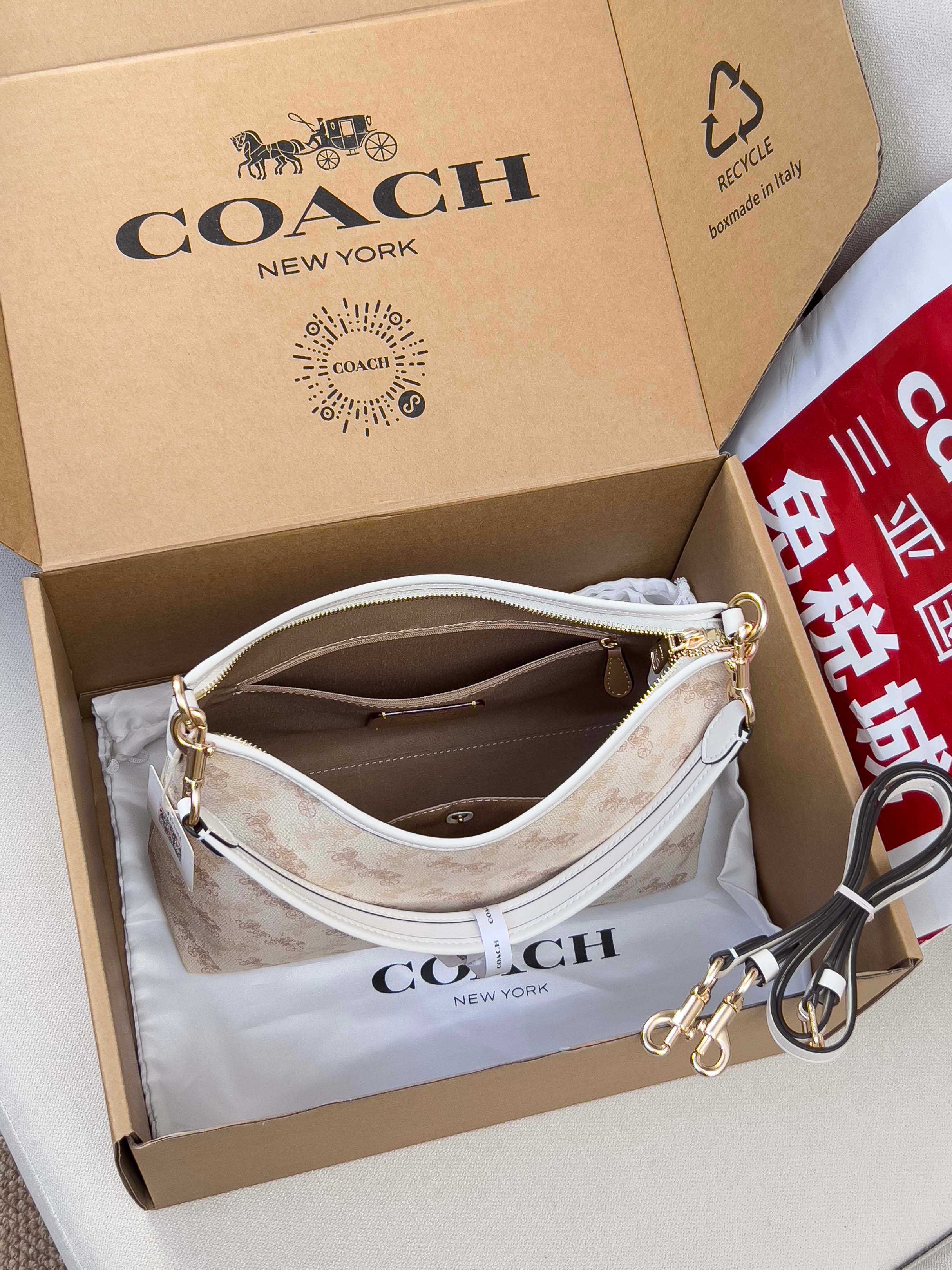 Light beige patterned crossbody bag with white strap, gold hardware, and inner zip opening