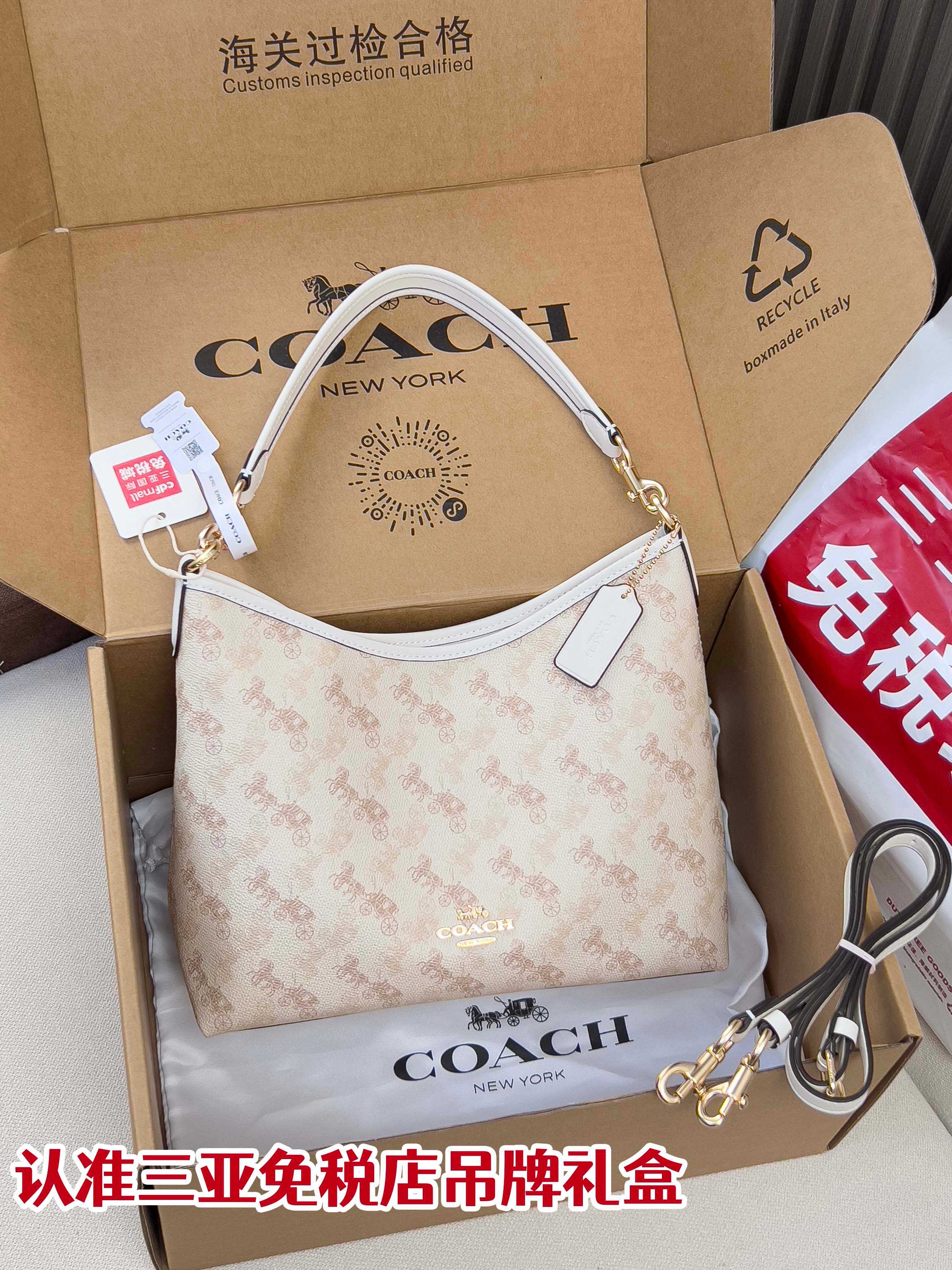 Light beige patterned shoulder bag with white handle, gold hardware, and hanging tag
