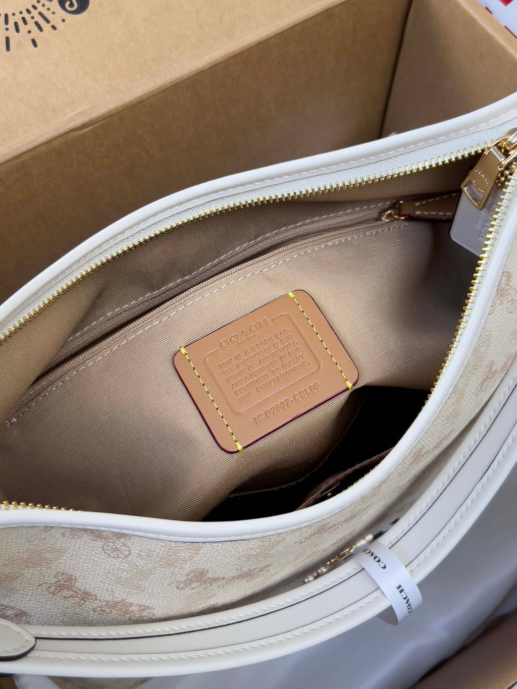 Light beige interior view of zip pocket with tan leather patch on handbag lining