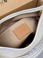 Coah handbag interior pocket with tan label inside beige lining, zip top edge