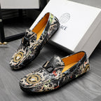 Printed slip-on loafers with black upper, gold medallion design, and orange lining