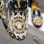 Close view of patterned slip-on loafers showing baroque medallion graphic on toe