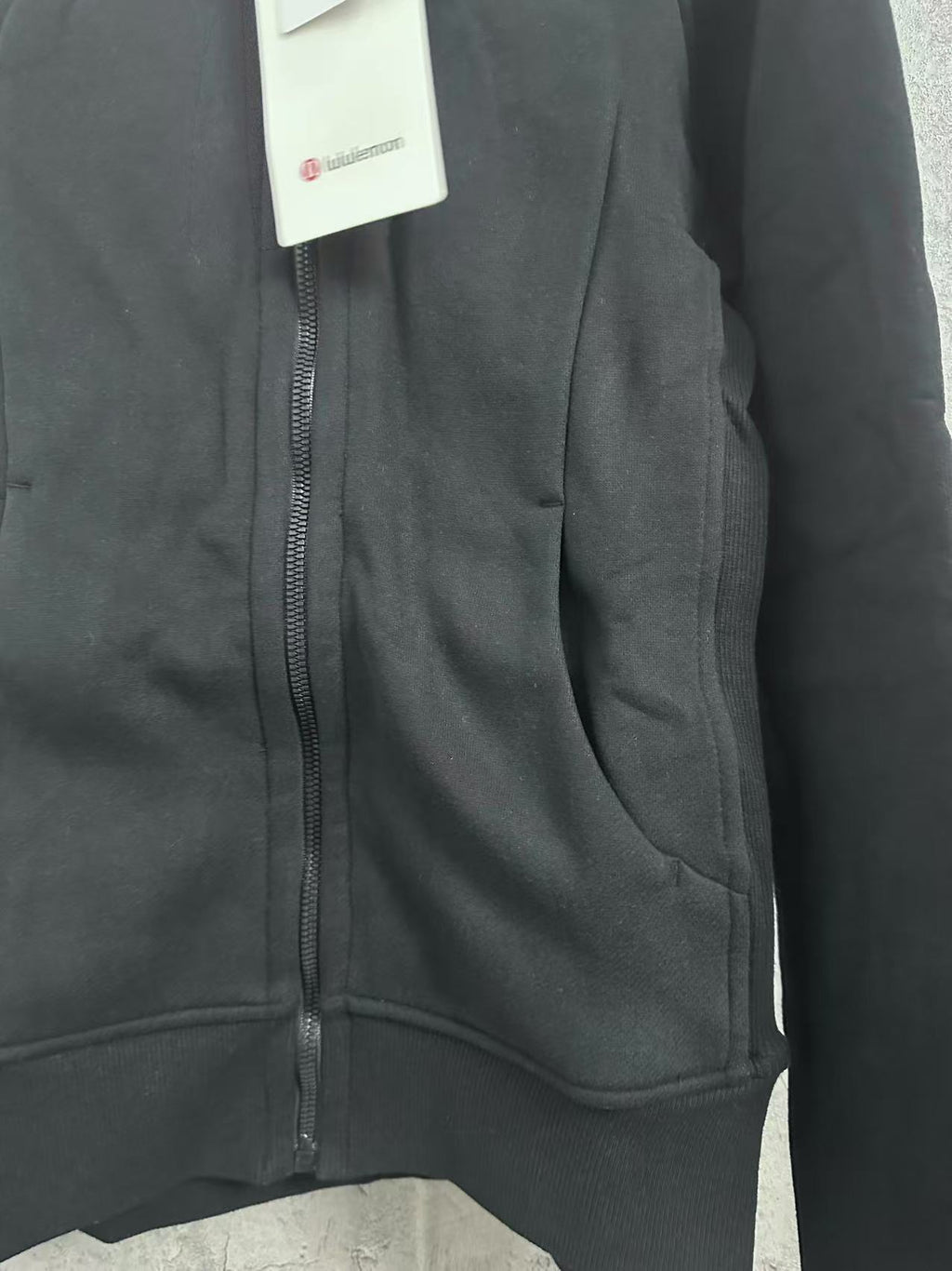 Dark hoodie zipper placket with curved pocket seam detail