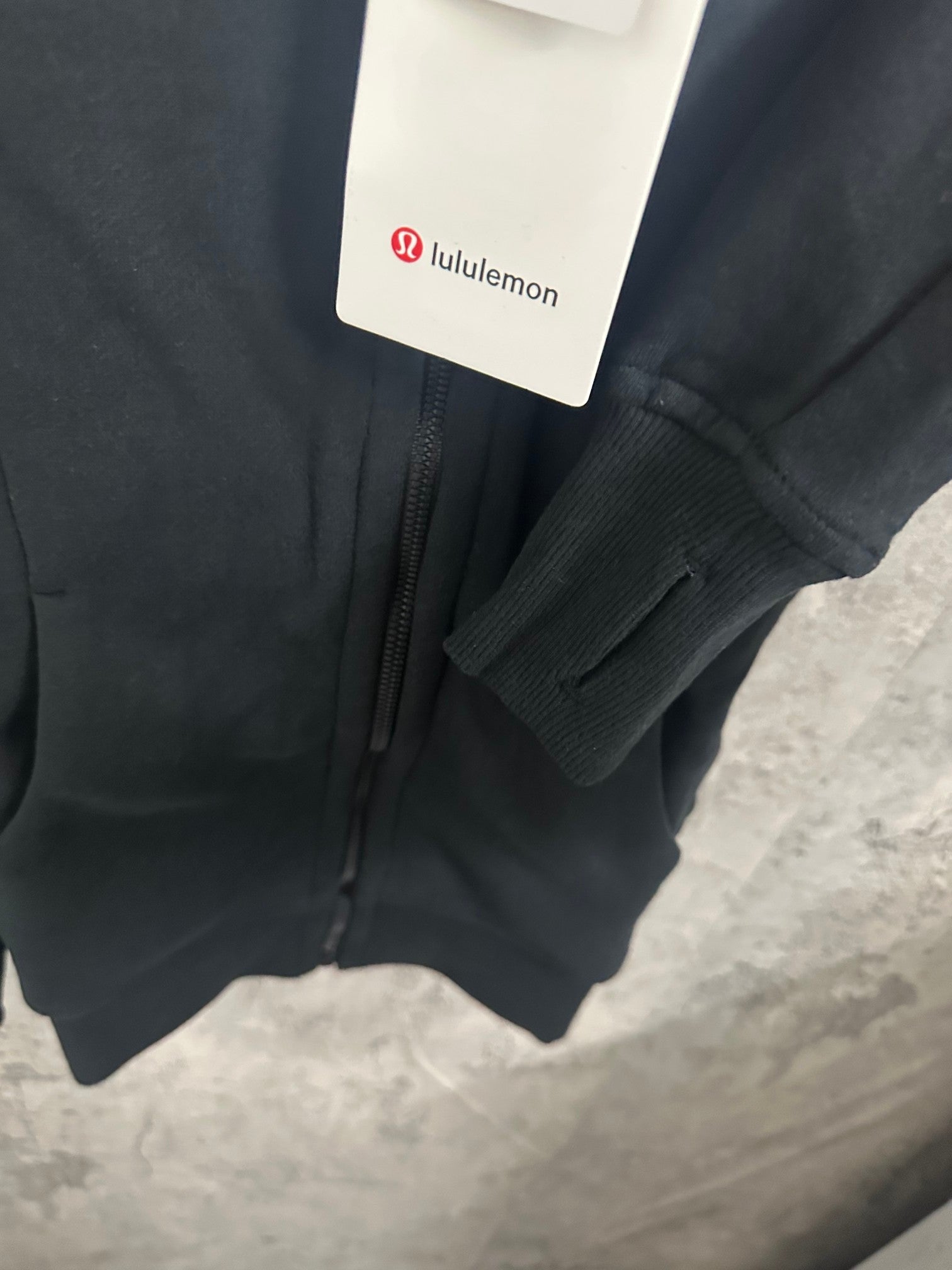 Dark hoodie sleeve cuff and zipper placket with hanging tag