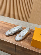 Pair of silver metallic loafers with gold-tone buckle detail and low-profile soles