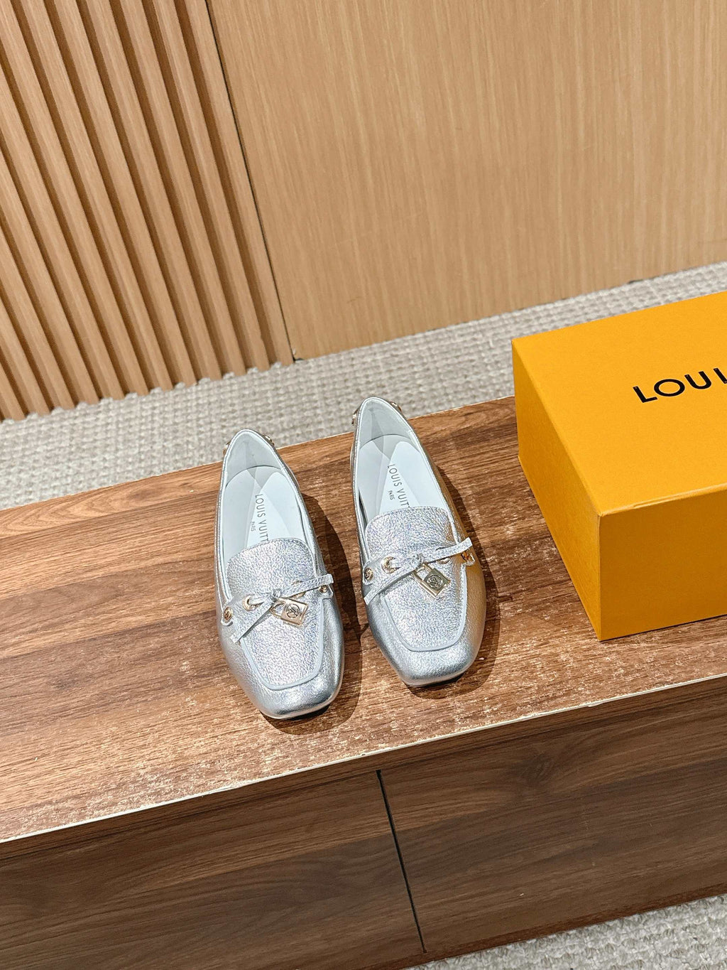 Silver metallic leather loafers with gold-tone buckle detail on the vamp