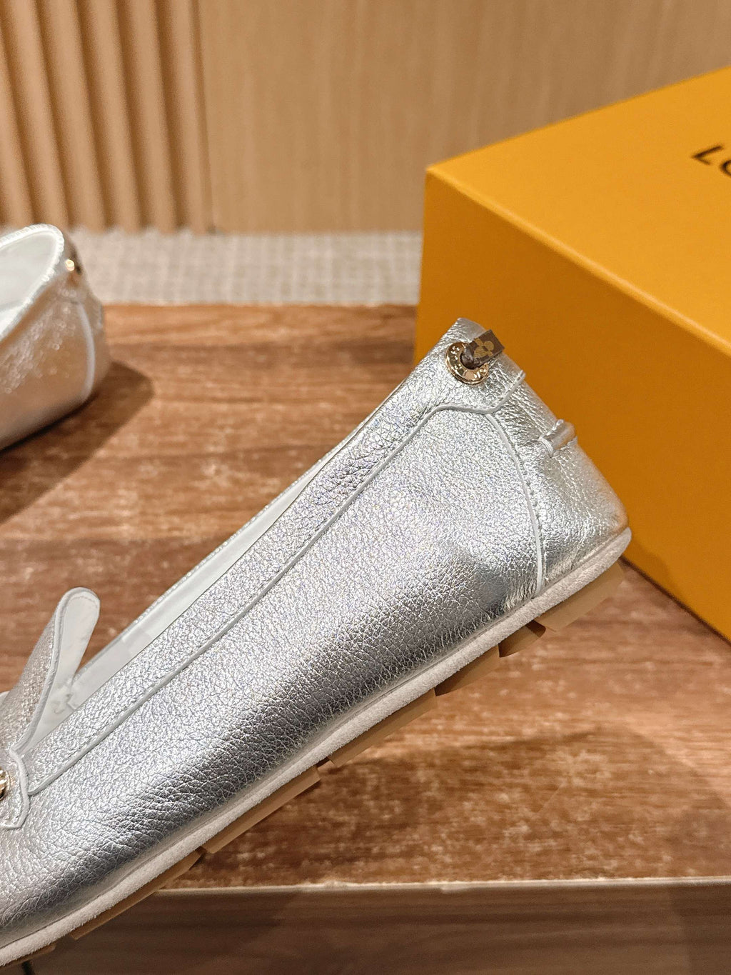 Silver metallic loafer side view with gold-tone buckle strap and stitched seams