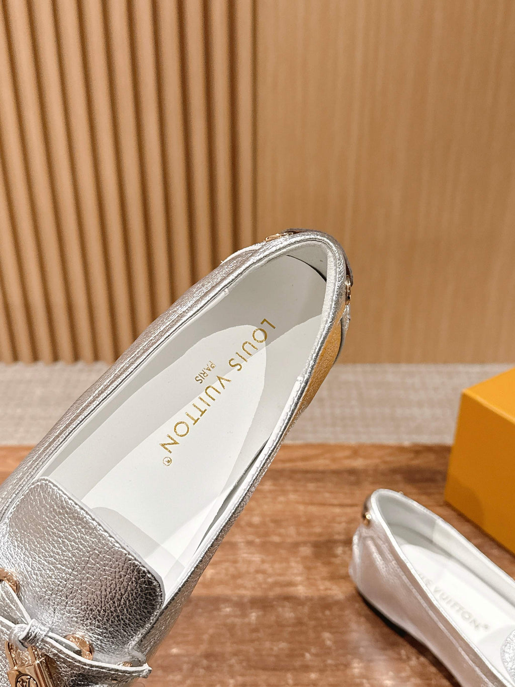 Silver metallic loafer showing inner lining and decorative gold-tone hardware