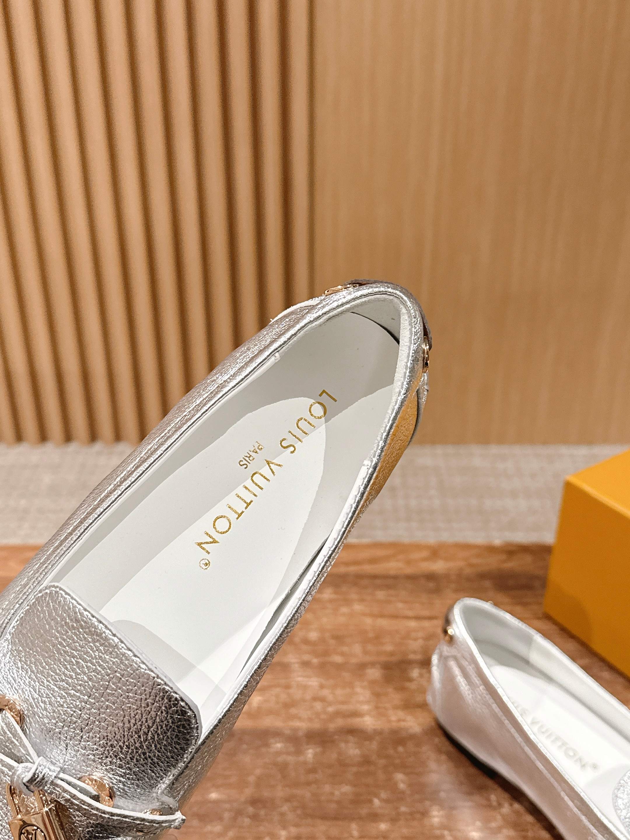 Silver metallic loafer showing inner lining and decorative gold-tone hardware