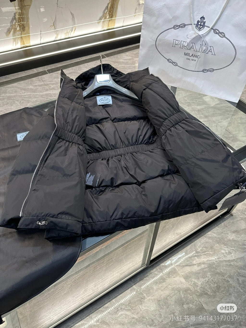 Black puffer jacket laid on display surface, hood and front zipper visible