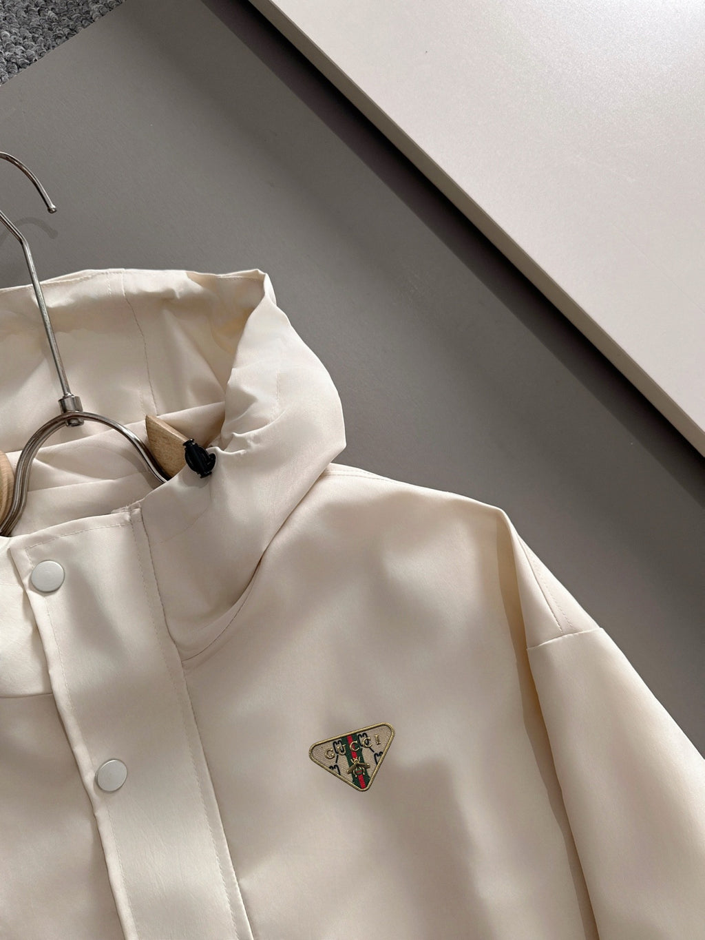Cream hooded long jacket with front zipper and small triangular logo patch