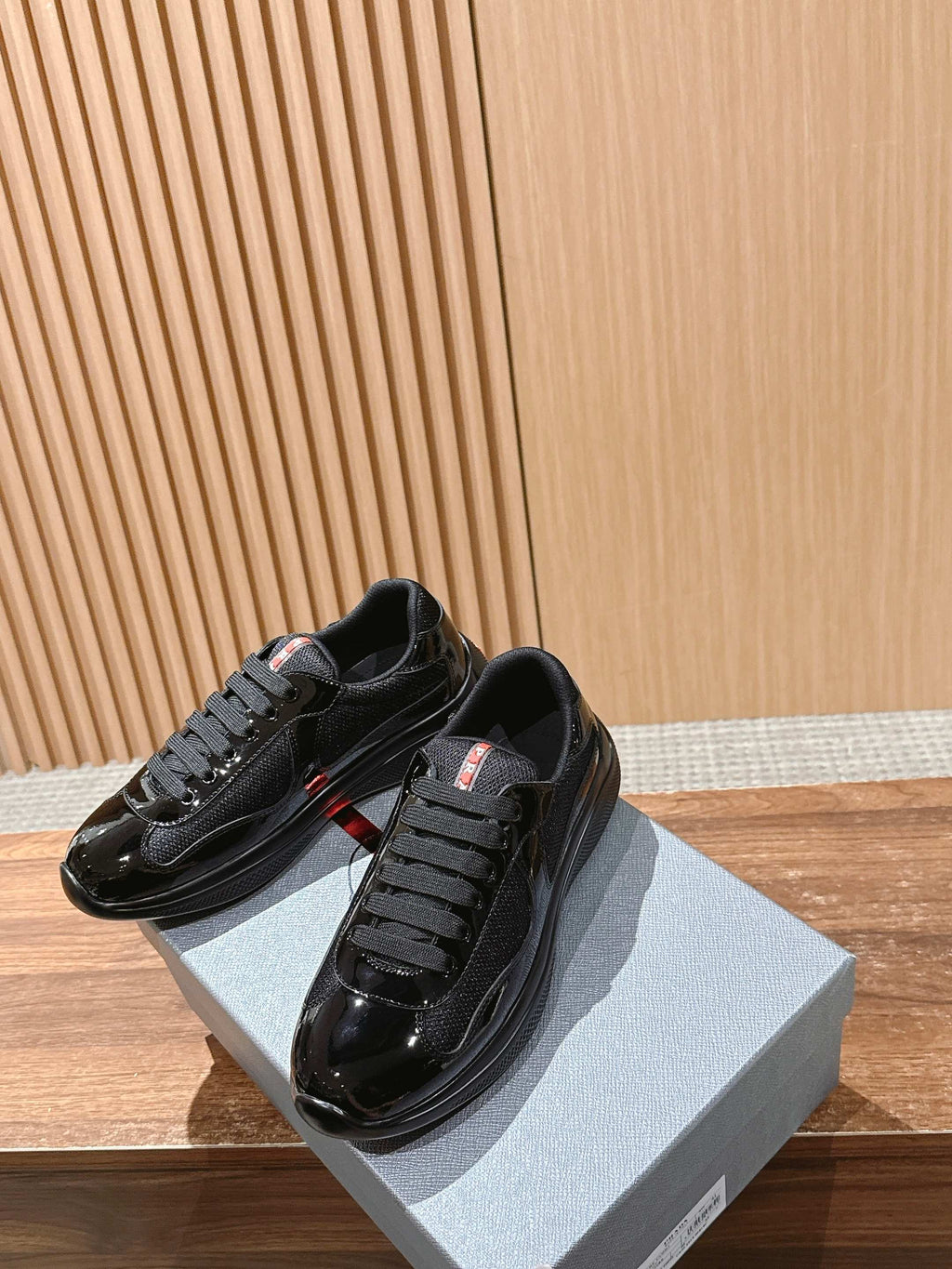 Black low-top lace-up sneakers with shiny toe cap and dark rubber sole