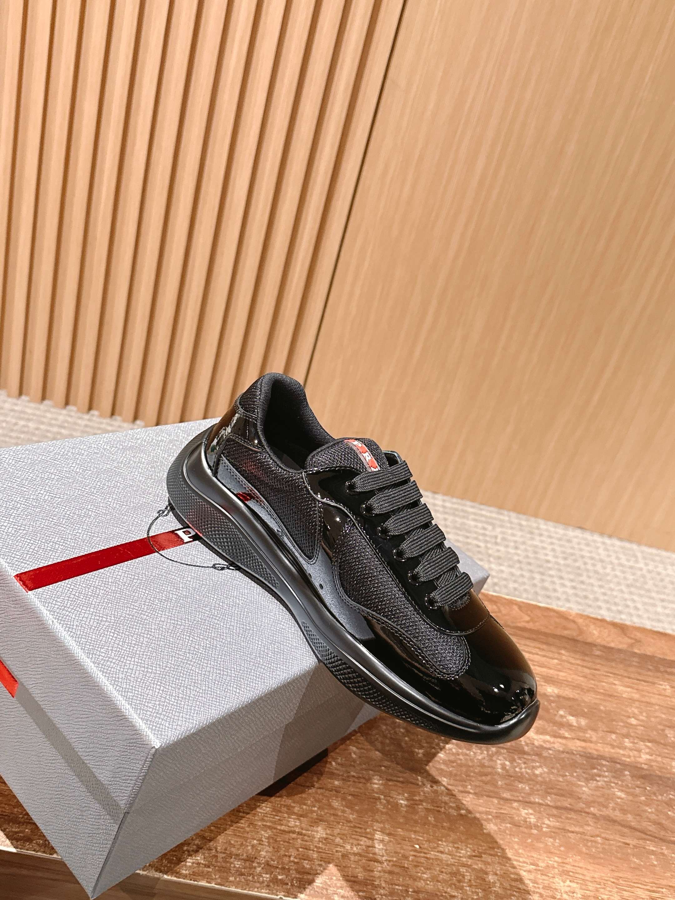 Black lace-up sneaker with glossy finish and padded collar, on light box