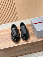 Black lace-up sneakers with glossy toe and textured sides, rubber sole