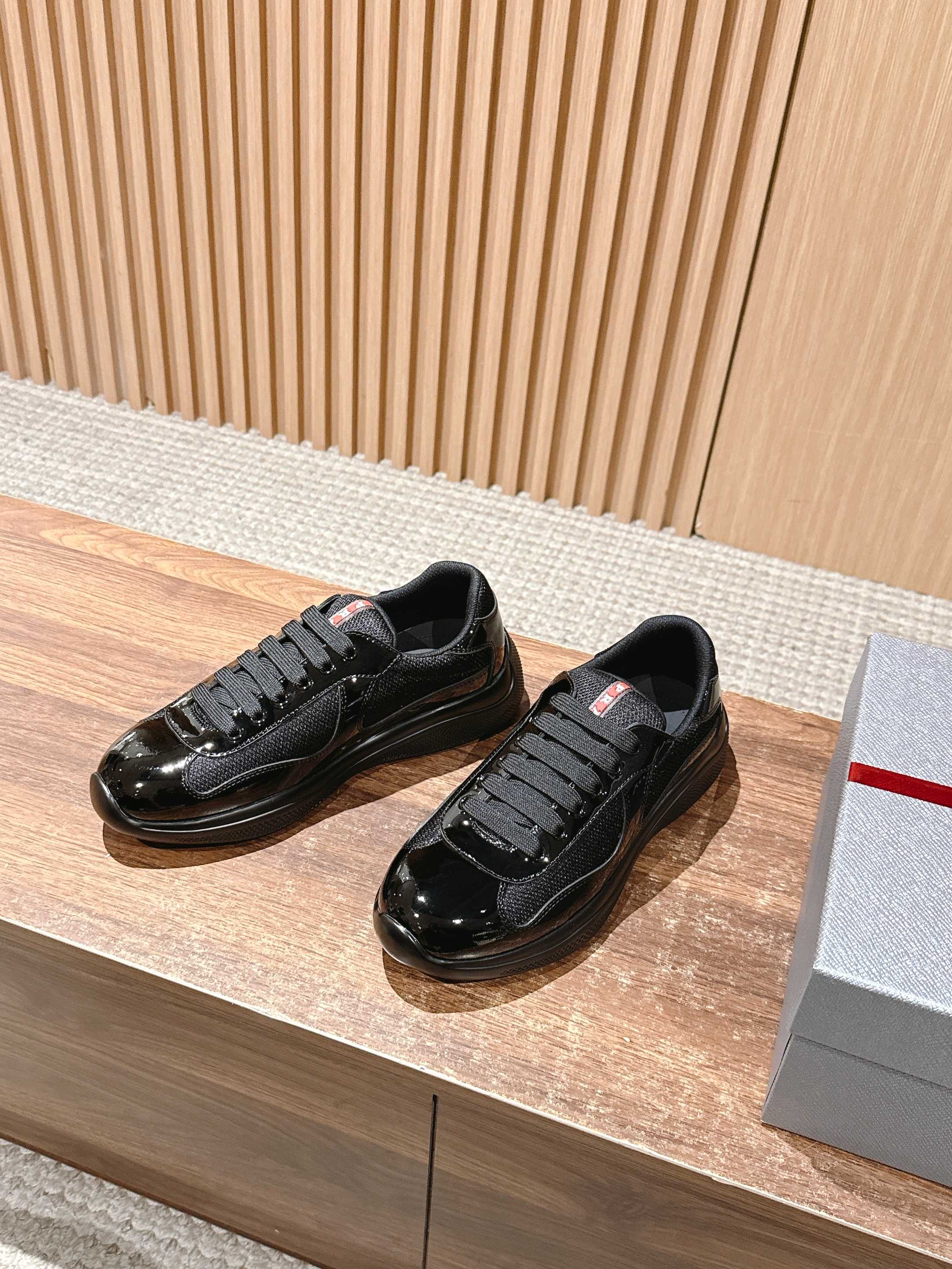 Pair of black lace-up sneakers on display, glossy front and lace-up closure