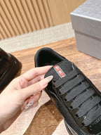 Black sneaker tongue with red and white logo patch, lace-up detail
