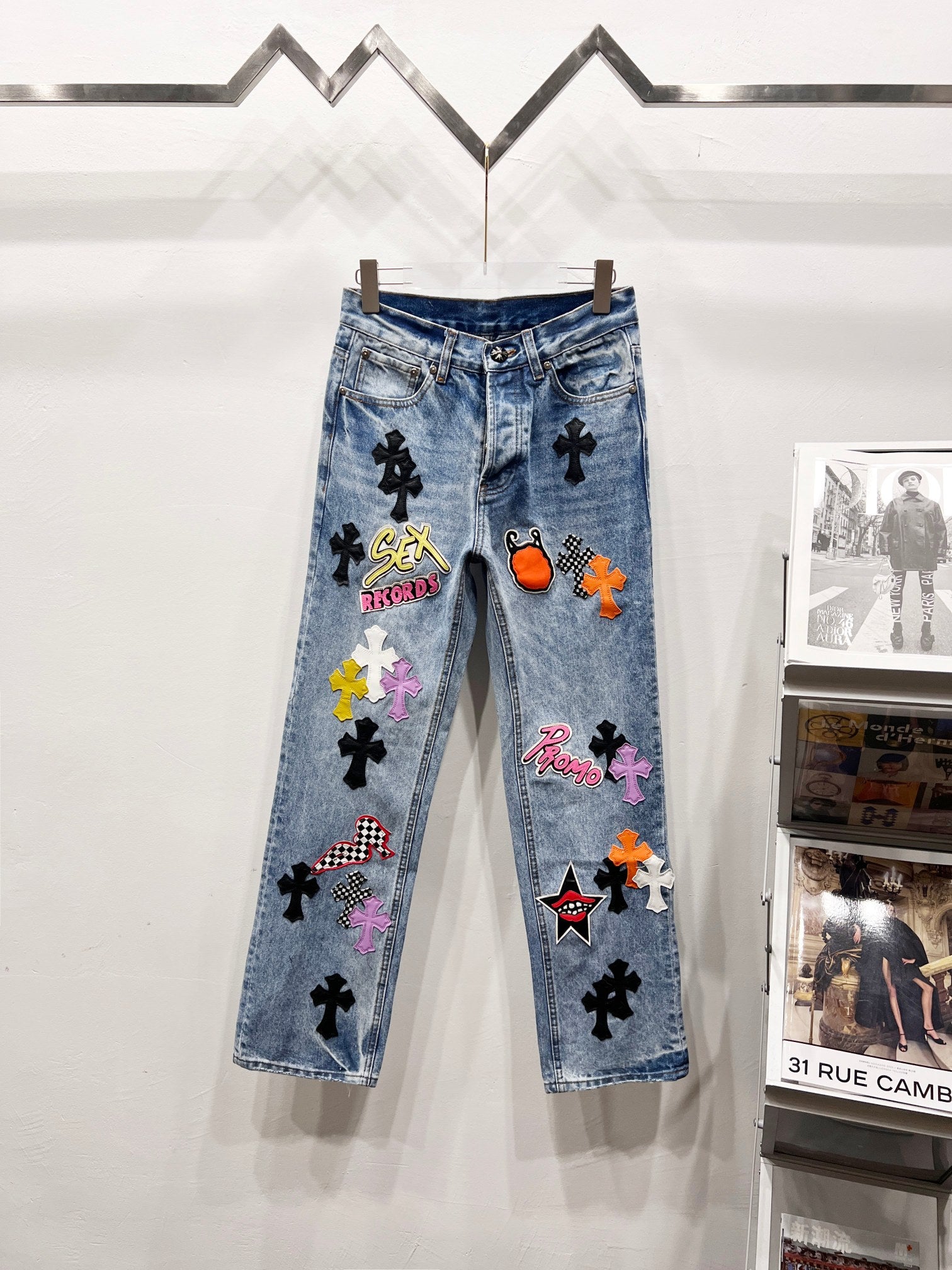 Light blue Chrome pants with colorful patch graphics and black cross motifs on legs