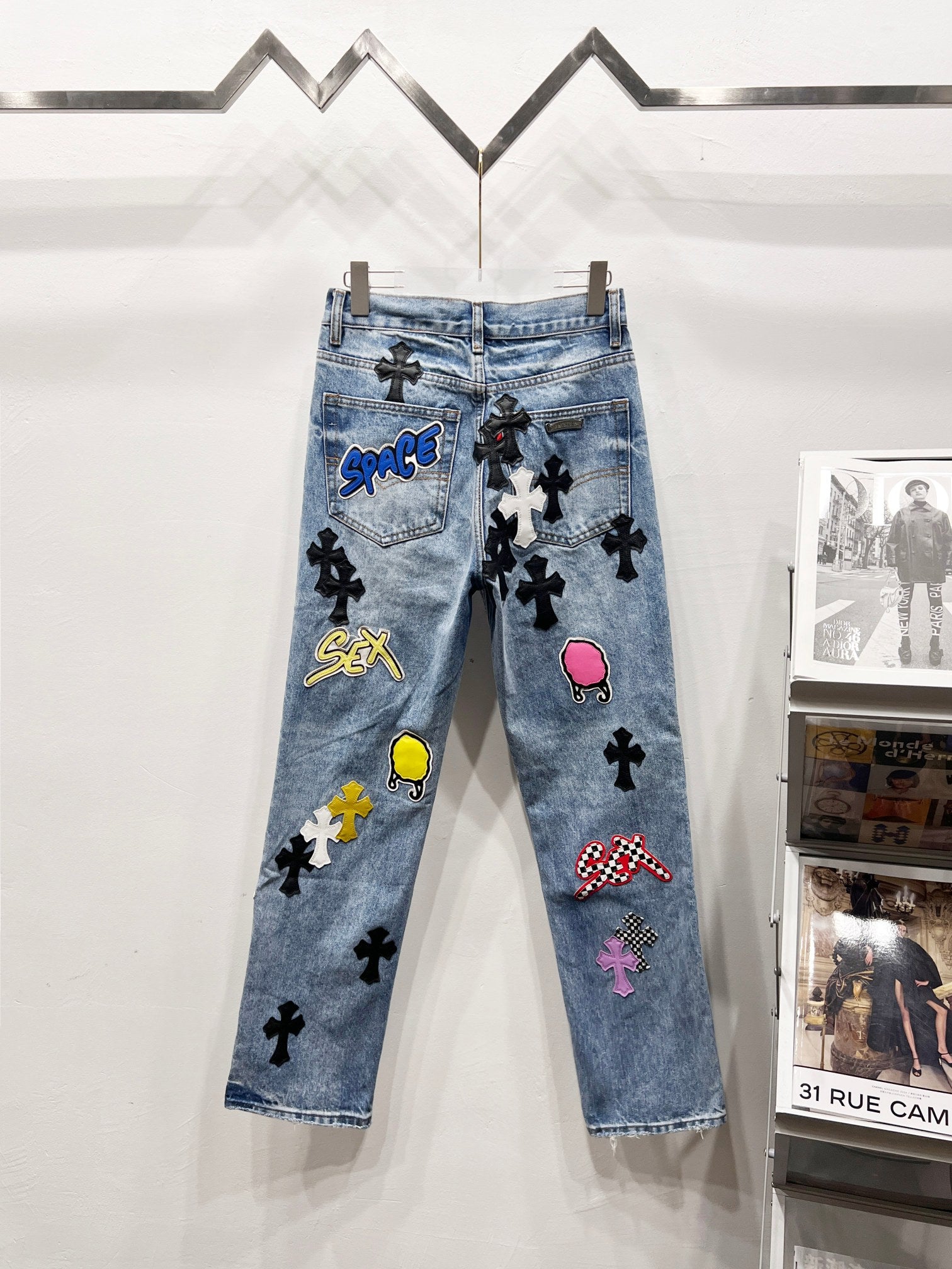 Light blue Chrome pants with patch graphics, black cross motifs, and a pink flamingo patch