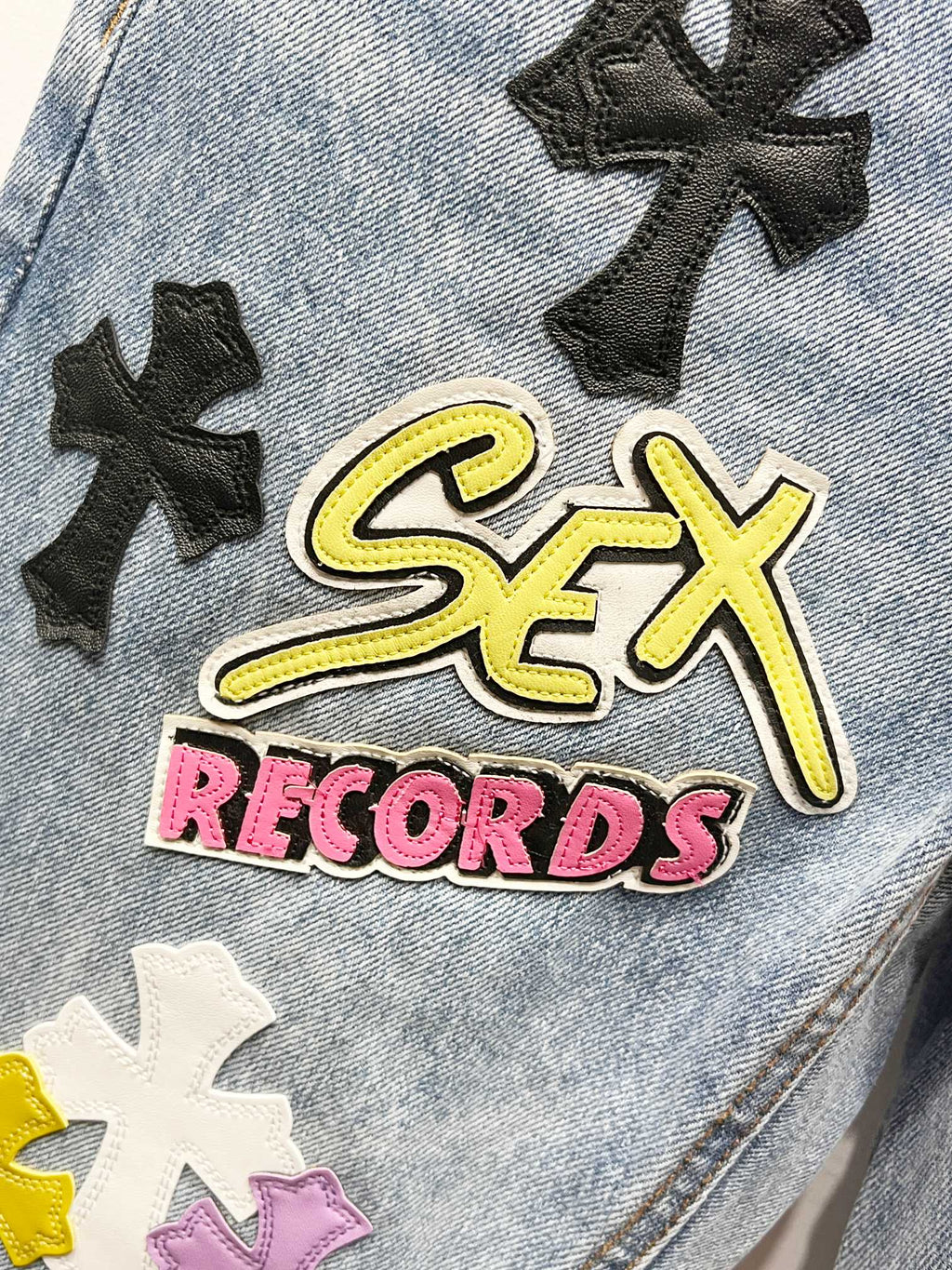 Light blue denim Chrome pants with bold 'Sex Records' embroidered patch and black cross motifs