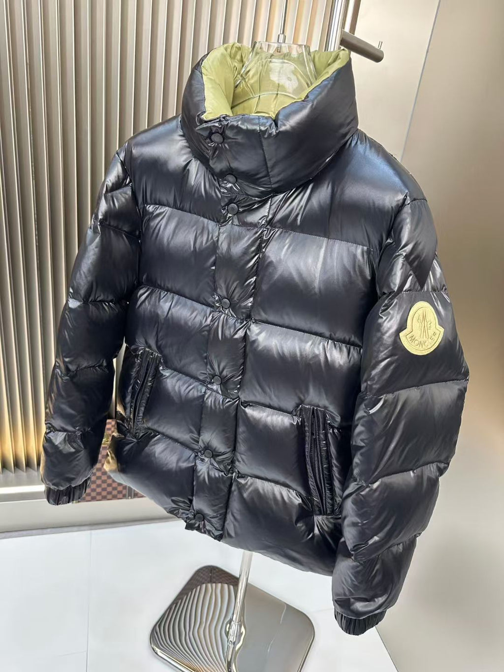 Long puffer jacket with black quilted exterior and neon green hood, front view