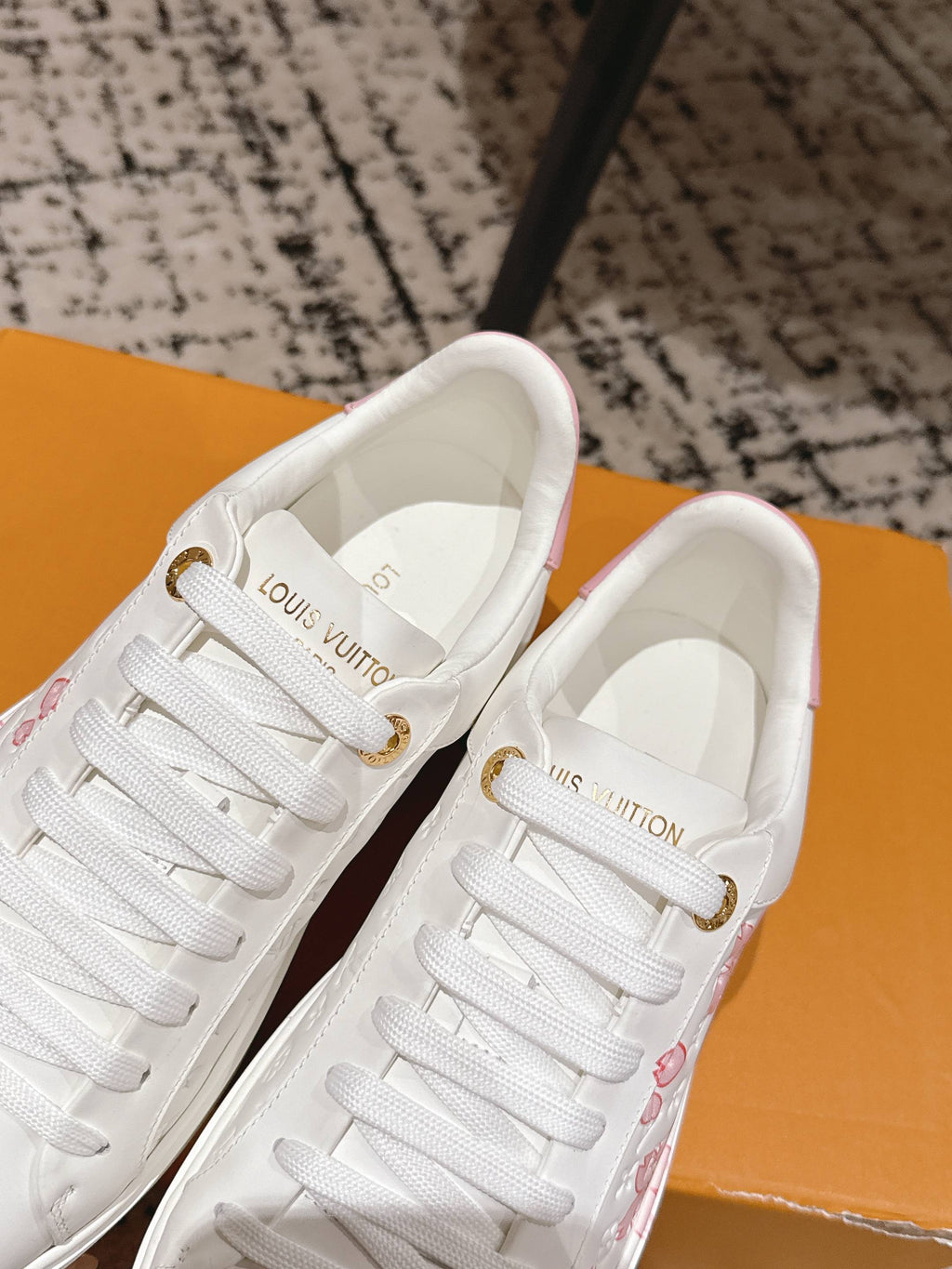 Louis Vuitton white sneakers with lace-up closure and pink floral accents on the side