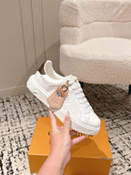 White low-top sneakers with tan and bear-like patch detail on the side