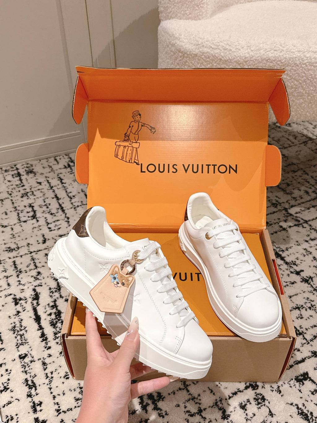 White low-top sneakers with gold-tone badge detail in open Louis Vuitton box