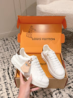 White low-top sneakers with gold-tone badge detail in open Louis Vuitton box