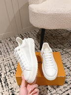 White low-top sneakers with textured side panel and white lace-up front