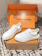 Pair of white low-top sneakers on orange Louis Vuitton boxes