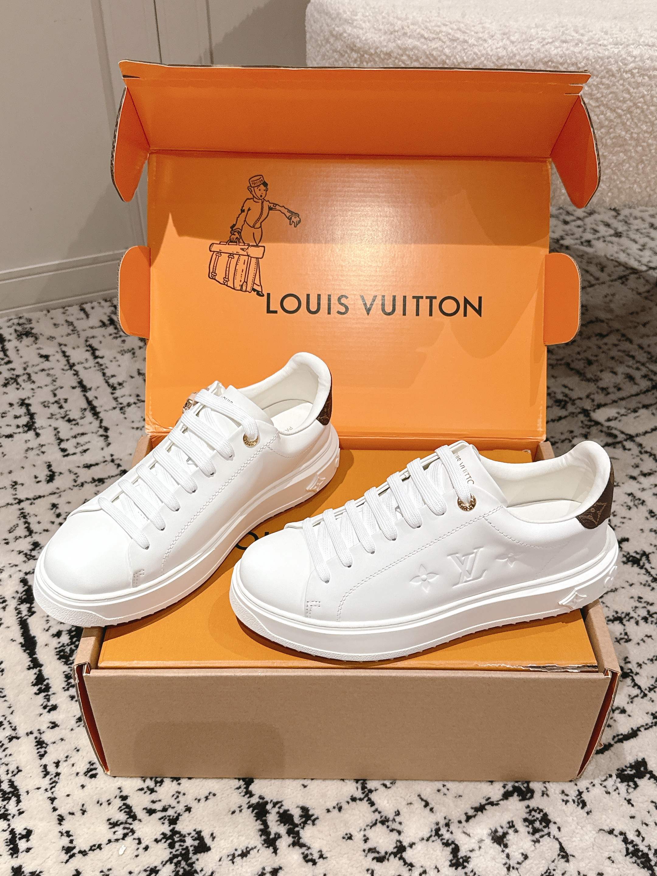 Pair of white low-top sneakers on orange Louis Vuitton boxes