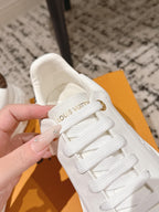 White low-top sneaker close-up with embroidered logo on the tongue