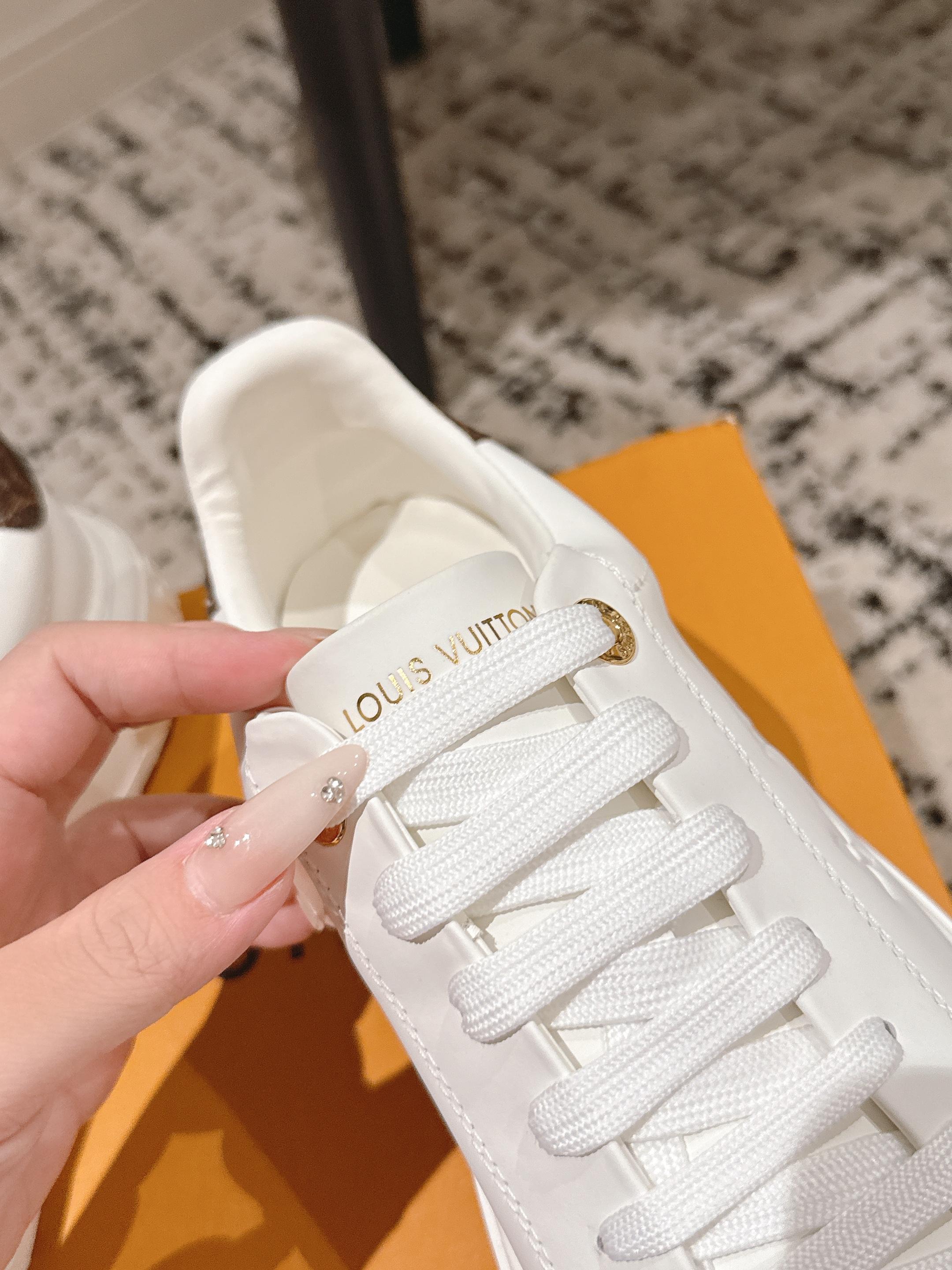 White low-top sneaker close-up with embroidered logo on the tongue