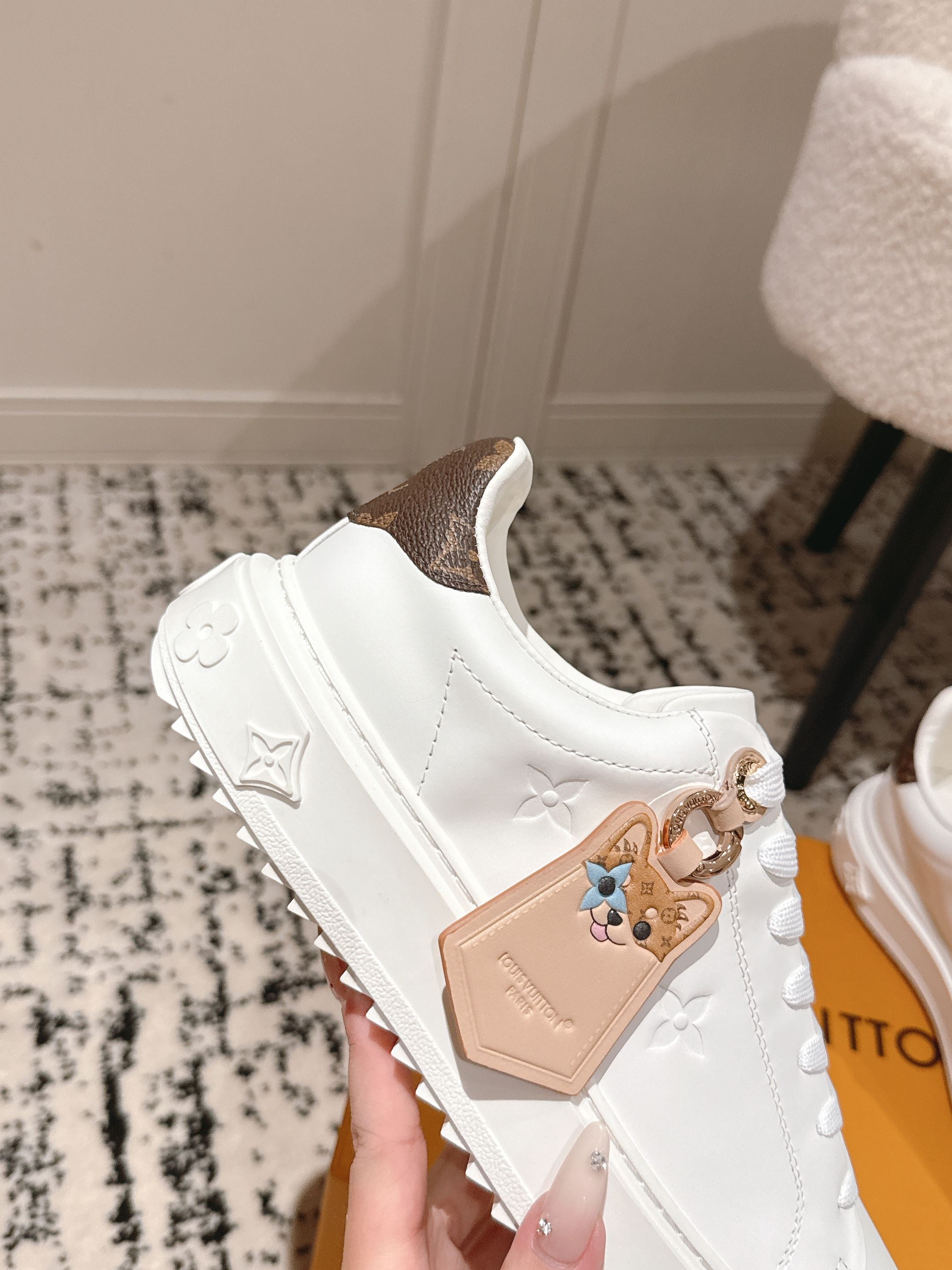 White low-top sneakers with tan patch and small logo pattern on side