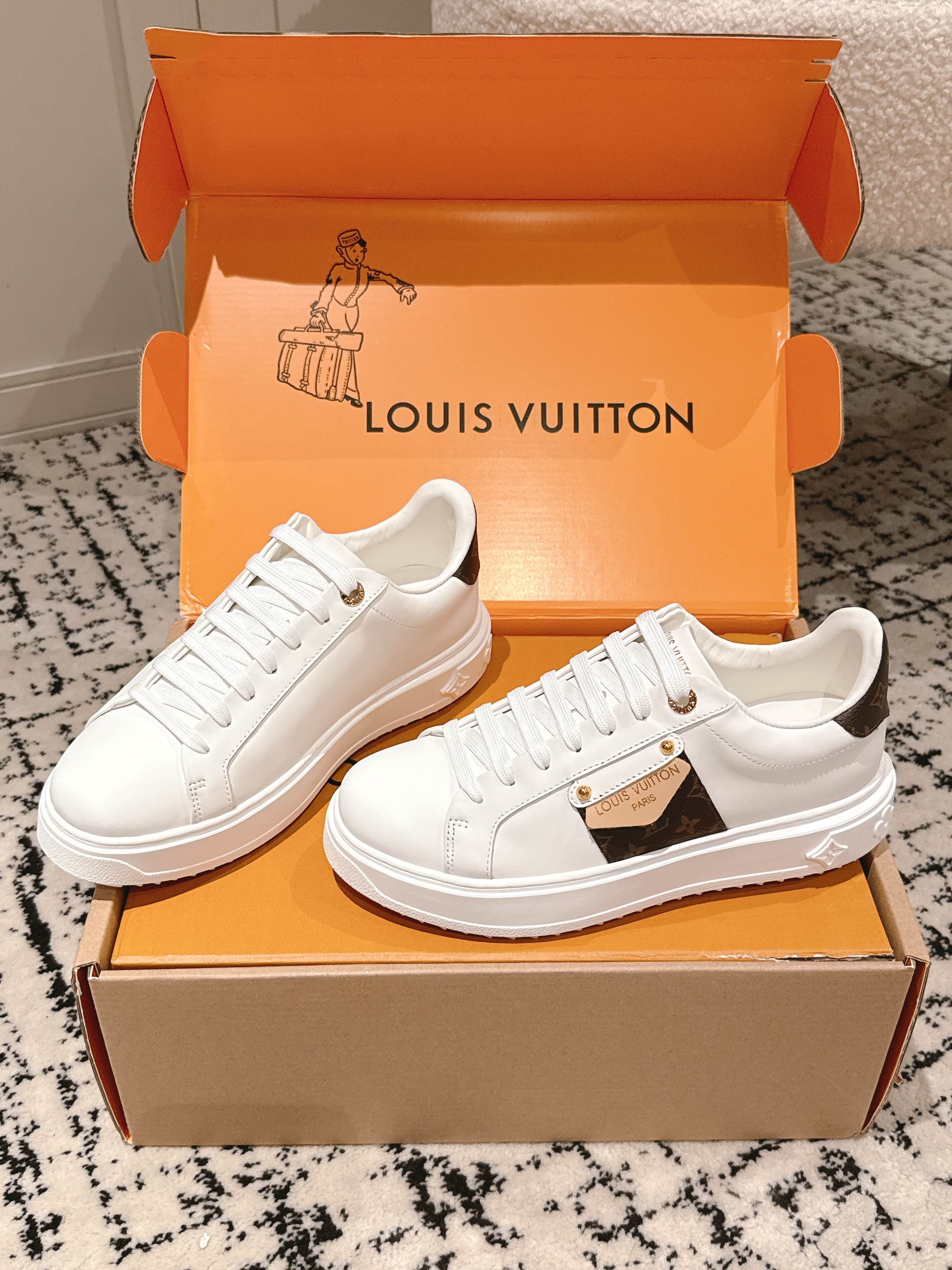 White Louis Vuitton low-top sneakers in open orange box with logo tongue detail