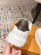 White low-top sneaker with dark-brown monogram heel patch and embossed heart on sole