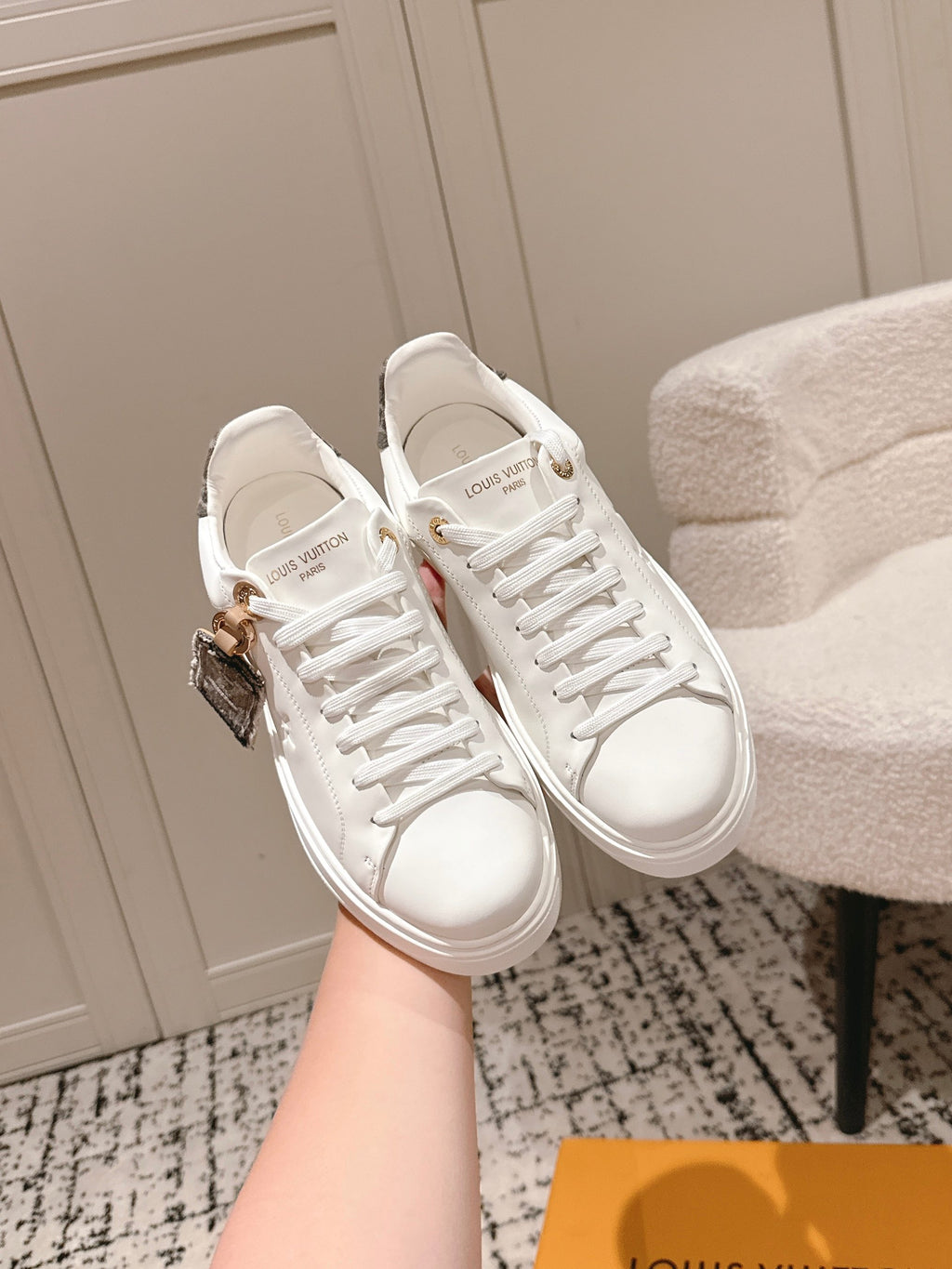 White low-top sneakers with lace-up front and gold-tone logo detail