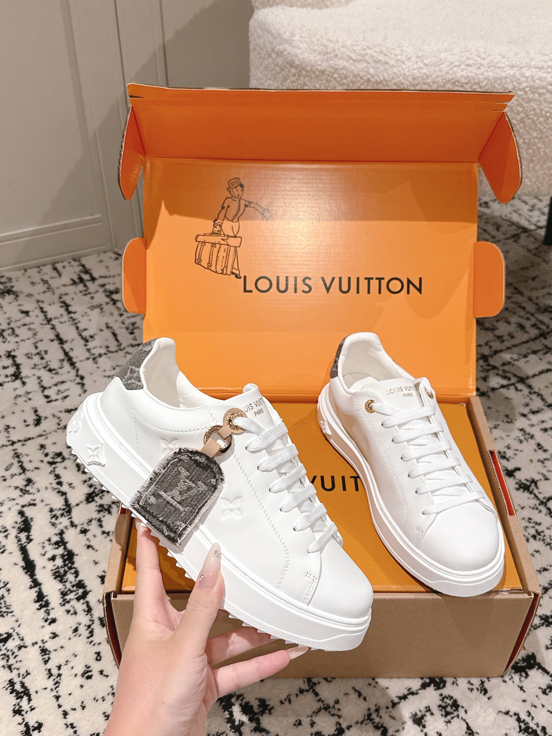 White low-top sneakers with lace-up closure and dark strap charm detail