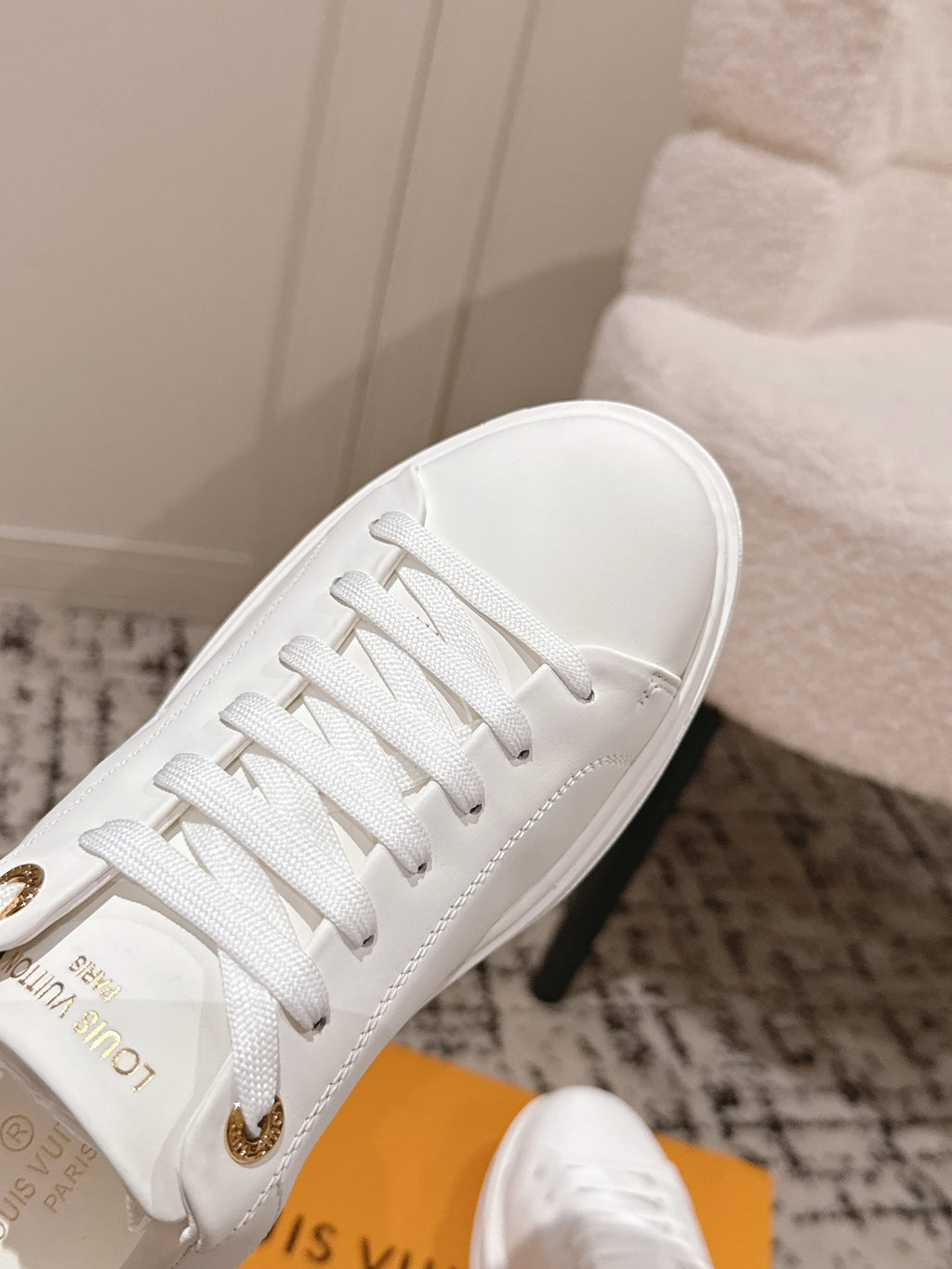 White low-top sneakers close-up of laces and gold-tone logo detail