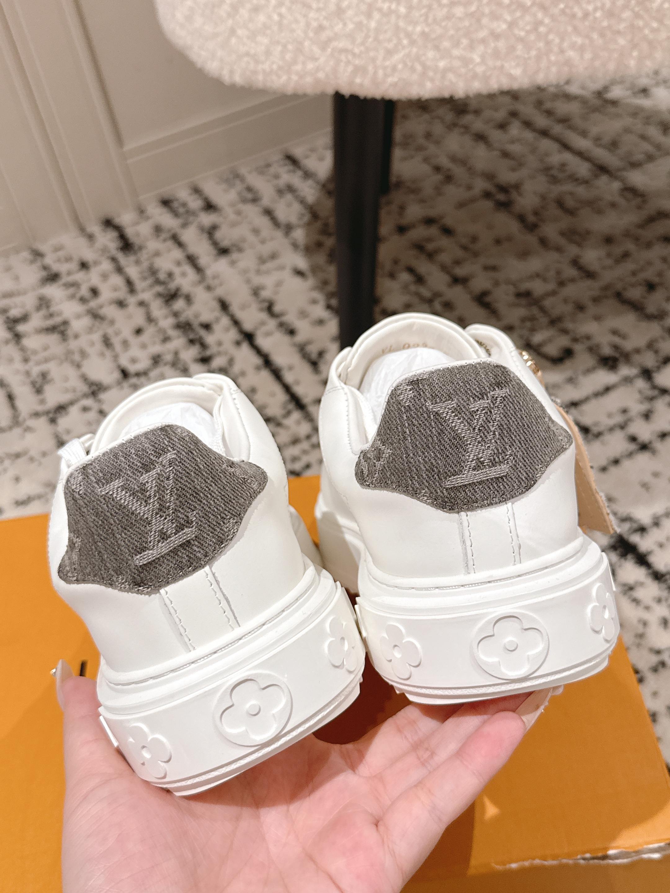 White low-top sneakers with gray monogram heel patch and embossed rubber back