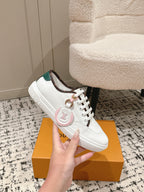 White leather low-top sneakers with green collar lining and small emblem