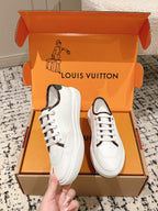 Pair of white Louis Vuitton sneakers with green heel lining, shown in open box