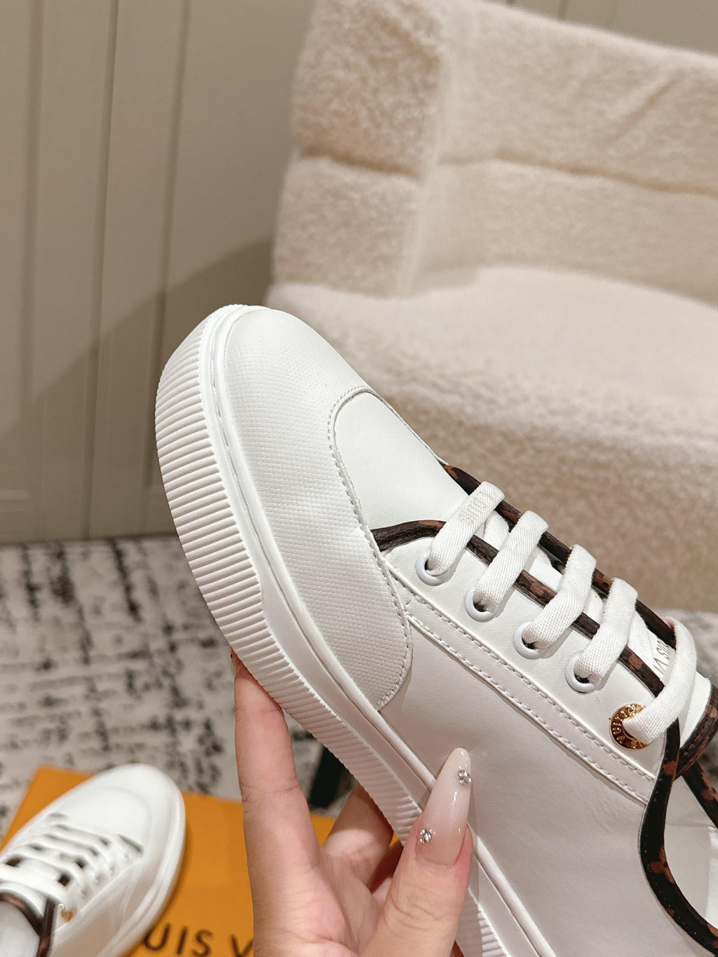 White Louis Vuitton leather sneakers with textured sole and white laces, close-up