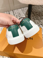 White leather sneakers with green heel panel and white ribbed sole