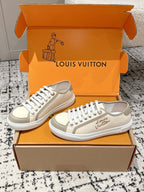 Cream low-top sneakers with white laces, textured toe cap, Louis Vuitton on side