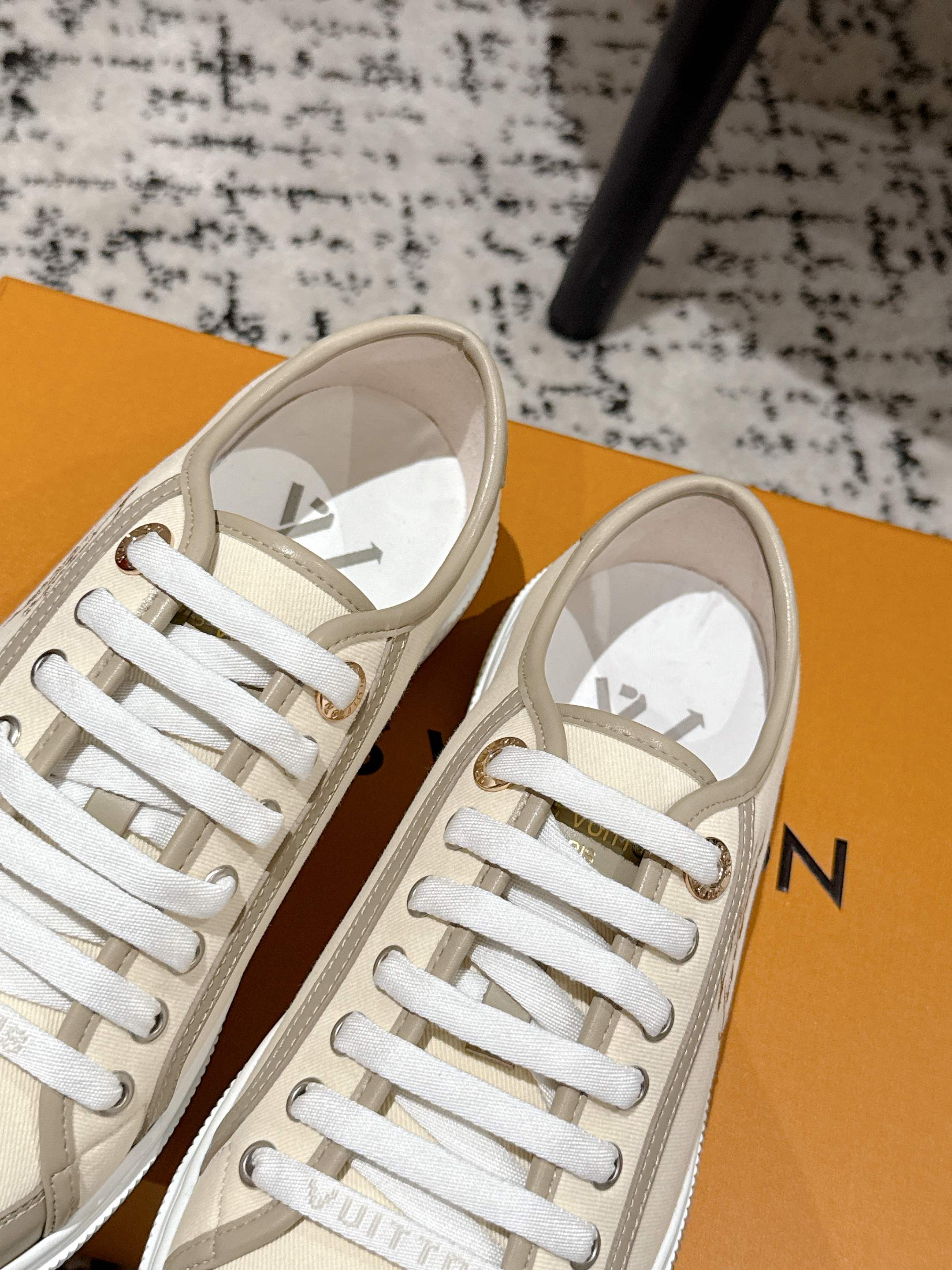 Two Louis Vuitton light beige low-top sneakers with white laces and off-white interior