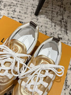 Gold leather sneakers with white laces, close-up of toe and tongue on shoebox.