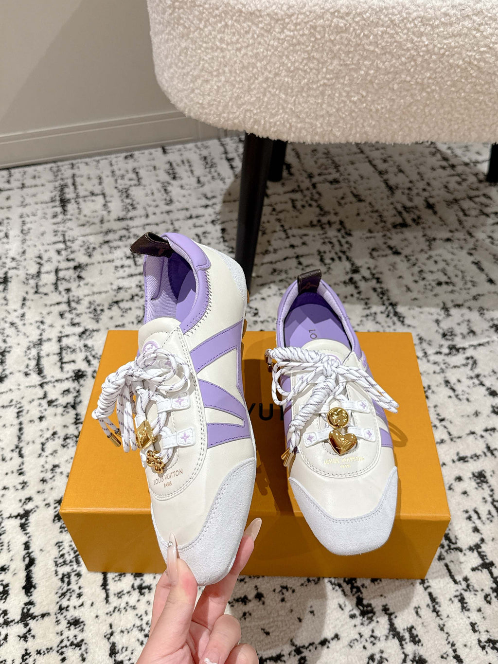 Close-up of white and lavender Louis Vuitton sneakers with gold emblem and crisscross laces