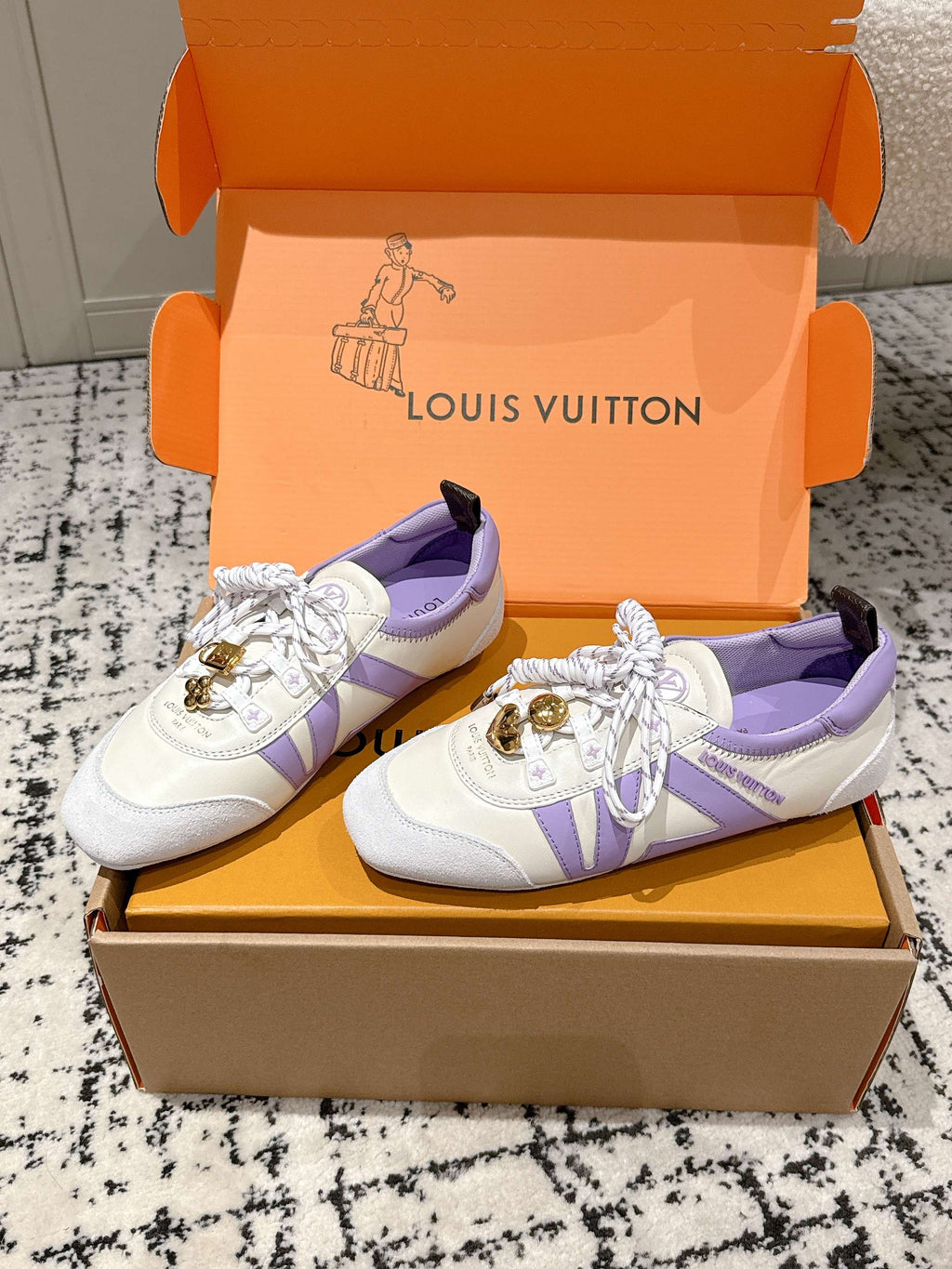 Louis Vuitton white sneakers with lavender side panels, gold emblem, and tied laces